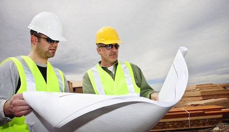 Two contractors reading construction plans at worksite