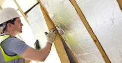 Builder Fitting Insulation Into Roof Of New Home