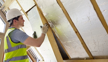 Builder Fitting Insulation Into Roof Of New Home