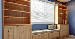 Empty lavender walls room. View of wooden storage combination with bench over the cabinets.