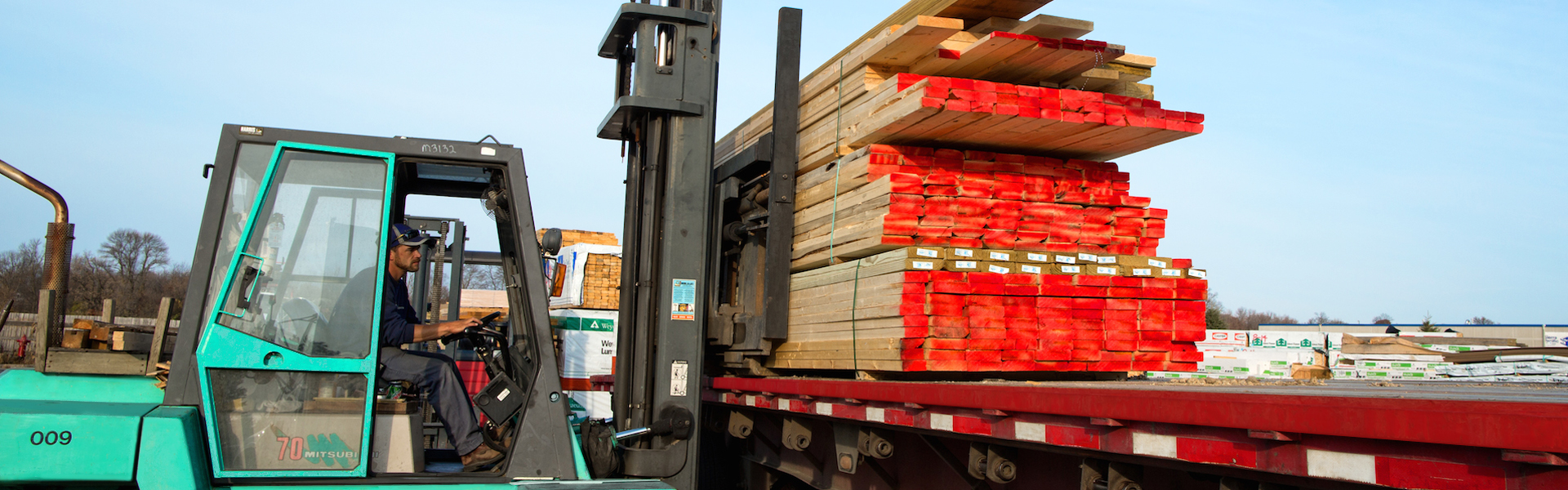 Lampert Lumber forklift loading a longbed Lampert Lumber Truck