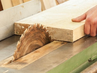 A close up of a woodworker's hand operating a piece of equipment