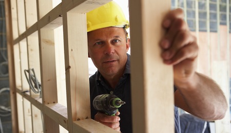 Construction Worker Building Timber Frame In New Home