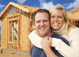 Happy Excited Couple in Front of Their New Home Construction Framing Site.