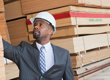 young male professional inspecting a lumber yard in suit and hard hat-10-25